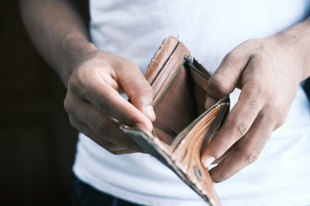 A person holding an open wallet, symbolizing financial struggle and the need for biblical debt management strategies."